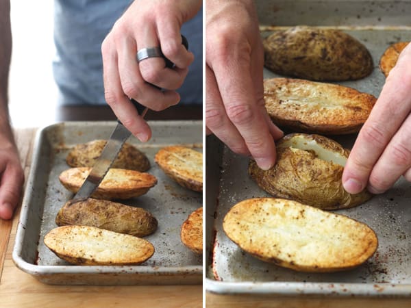 Baked potato halves on a sheet pan sliced and pressed open.