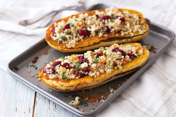 Roasted delicata squash boats stuffed with a quinoa salad on a small sheet pan.