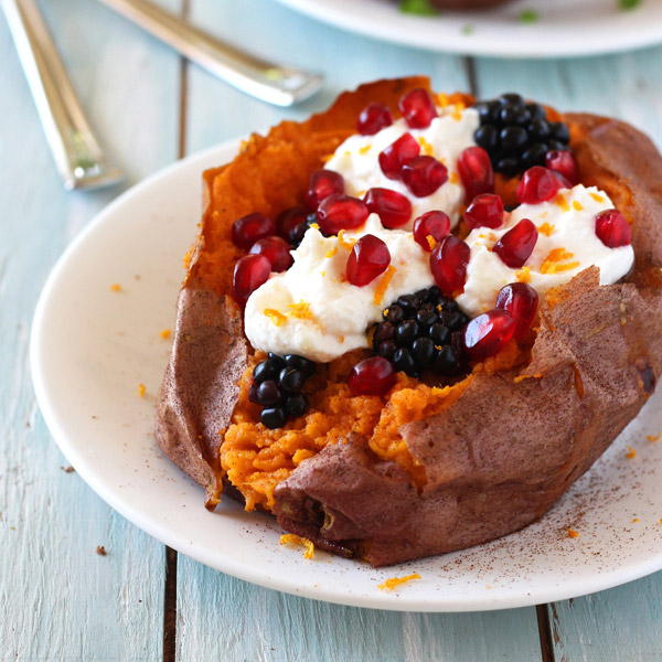 Blue wooden table with a stuffed sweet potato on a plate.