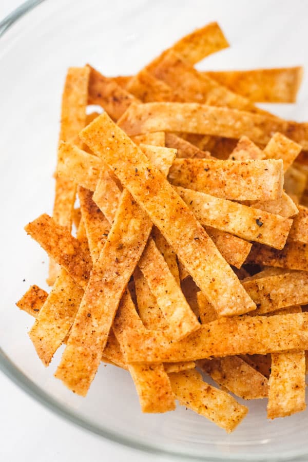 Taco seasoning coated tortilla strips in a glass bowl.