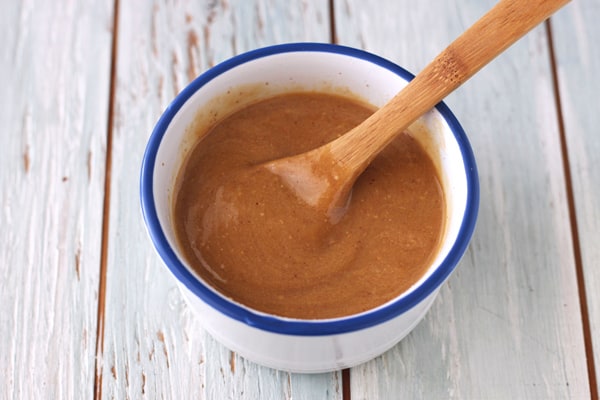 Wooden spoon stirring a peanut butter mixture in a small ramekin.