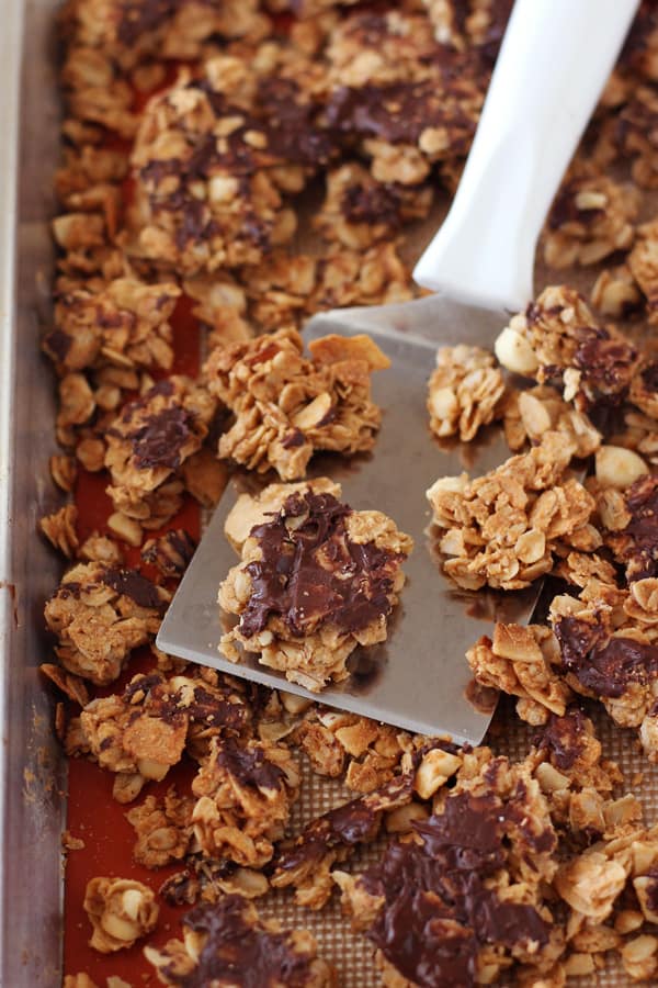 Peanut butter granola broken into clumps on a baking pan.