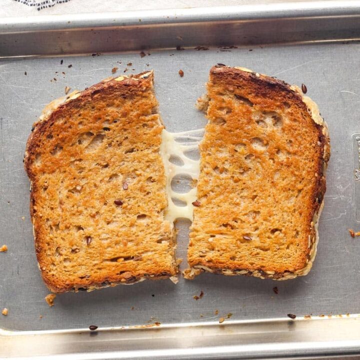 Golden baked grilled cheese split in half on a pan.