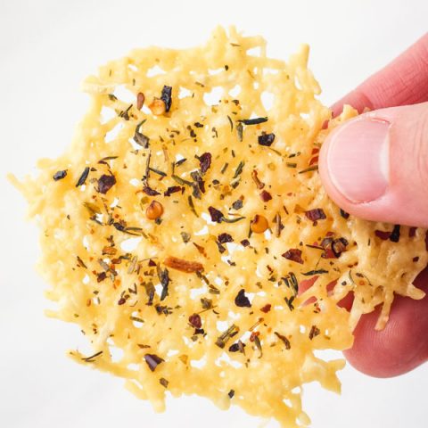 A hand holding a parmesan crisp.