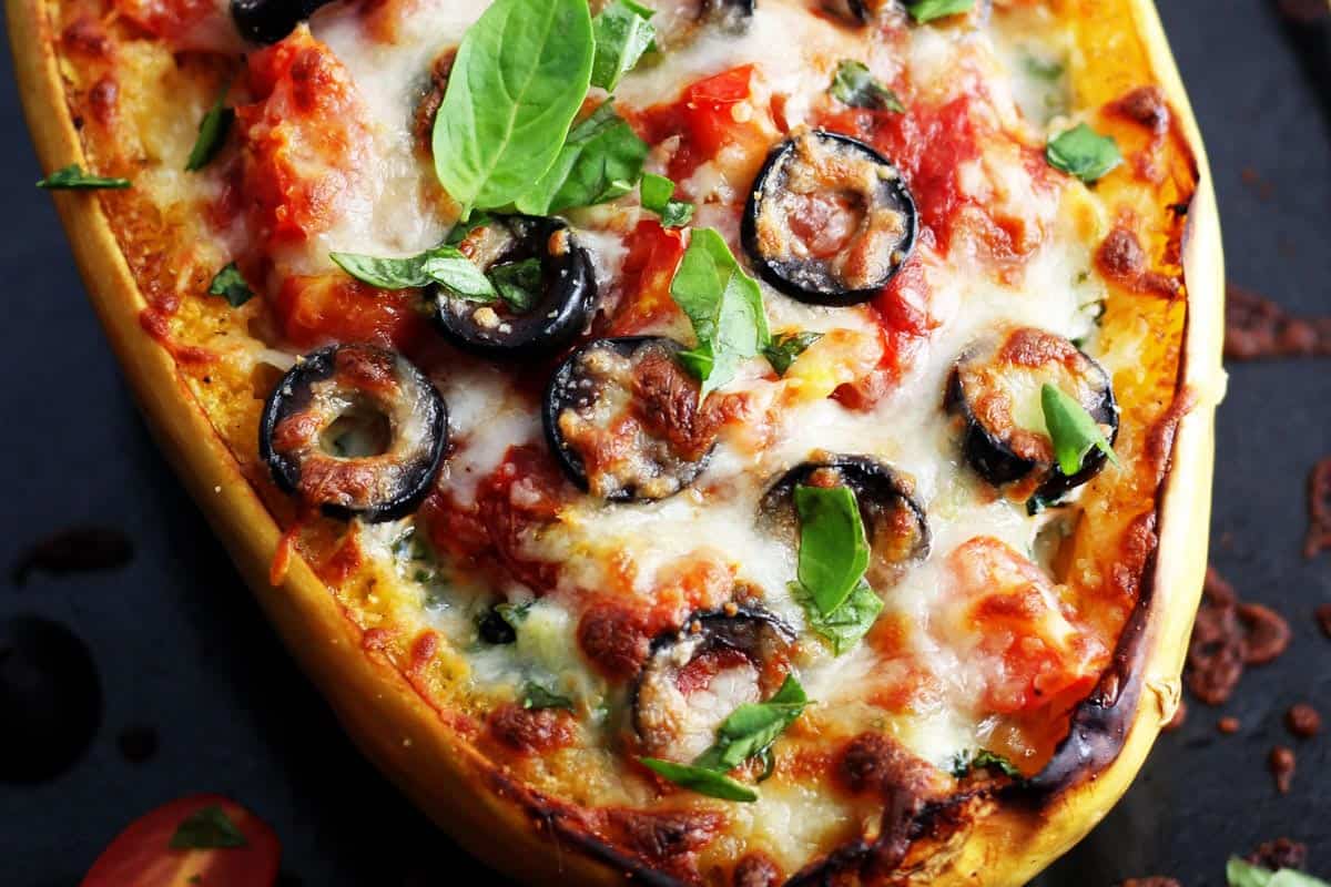 Close up of cooked spaghetti squash boat with melted cheese and black olives.