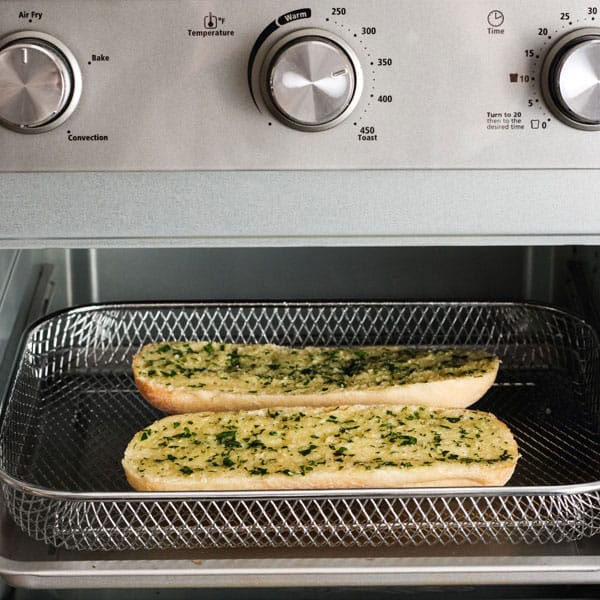 Garlic bread in air fry basket inside of a toaster oven.