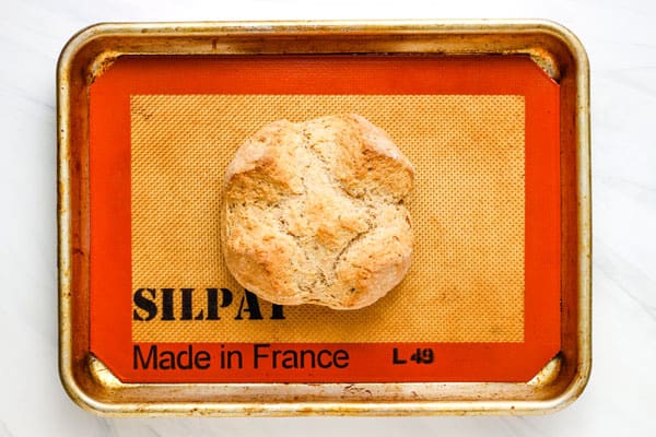 Baked mini bread loaf on lined quarter sheet pan.