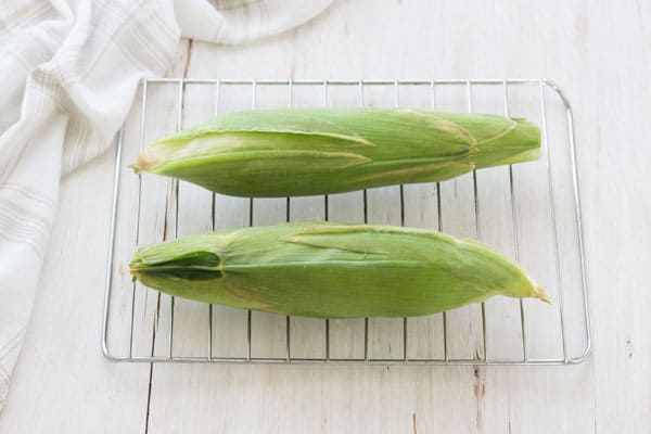 Two corn cobs on a small toaster oven cooking rack.