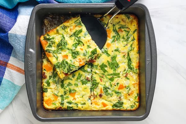 Overhead view of spatula lifting a slice of egg bake out of a pan.