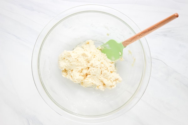 Mixed biscuit dough in a glass bowl with a rubber spatula.