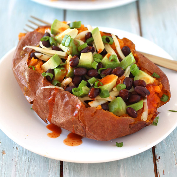 A blue table with a white plate with a fork and stuffed sweet potato.