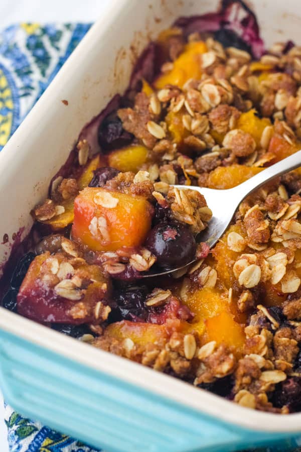 Spoon scooping into a blueberry mango fruit crisp.