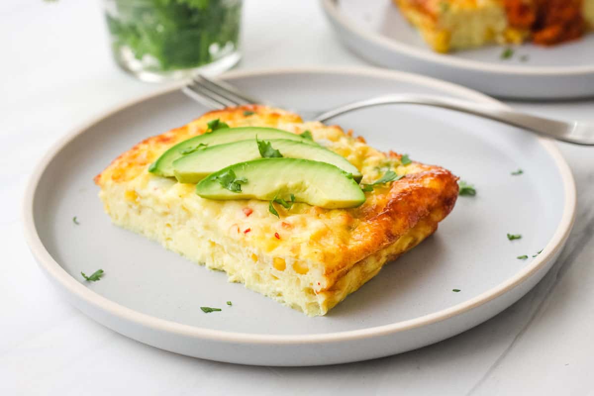 Plate of egg bake topped with avocado slices and cilantro.