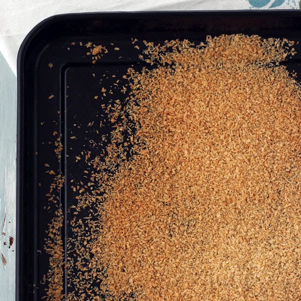 Toasted coconut on a dark roasting pan.