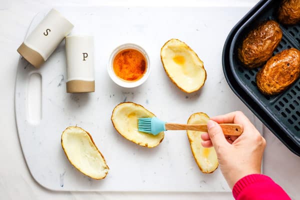 Hand brushing potato scoops with seasoned oil.