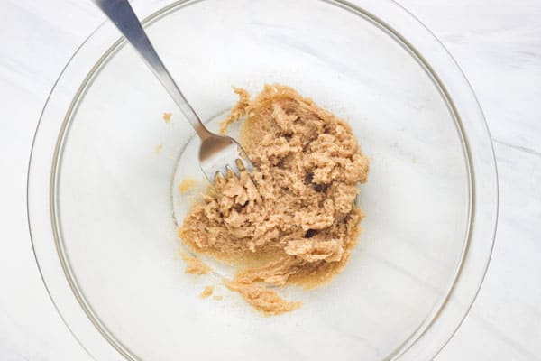 Butter and sugar creamed with a fork in a bowl.