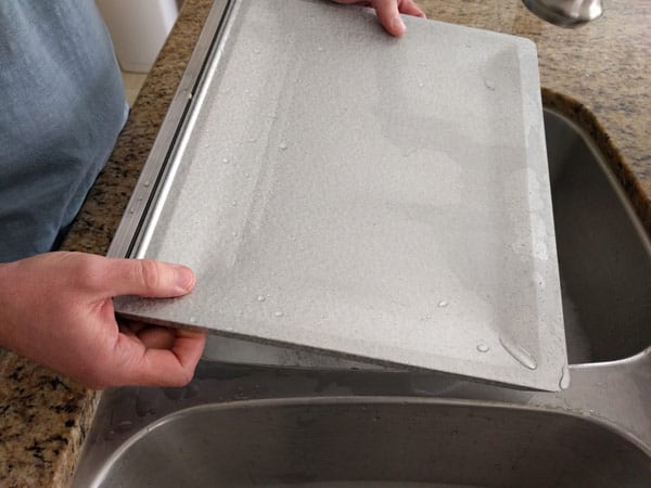 Hands holding a clean toaster oven crumb tray.