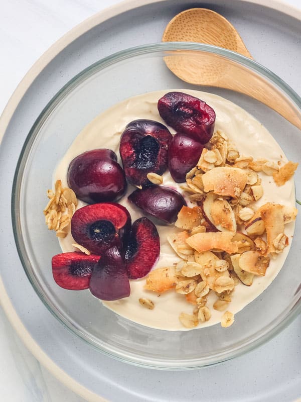 Overhead view of cherries and granola on a bowl of coffee yogurt.