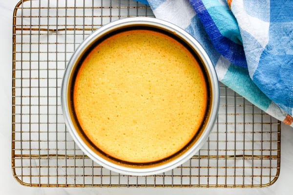 Baked cake in a 6-inch pan cooling on a rack.