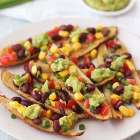 Potato skin strips on a plate with bean salsa and guacamole.