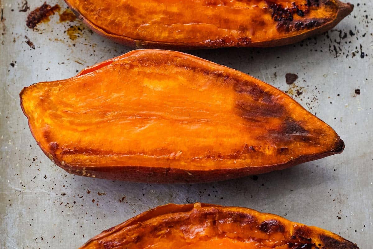 Roasted sweet potato halves on a sheet pan.