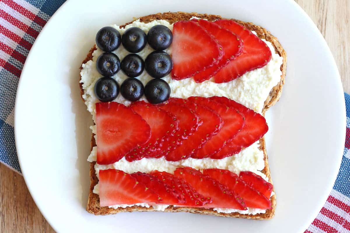 Ricotta cheese topped toast with blueberries and strawberry slices arranged like the American Flag.