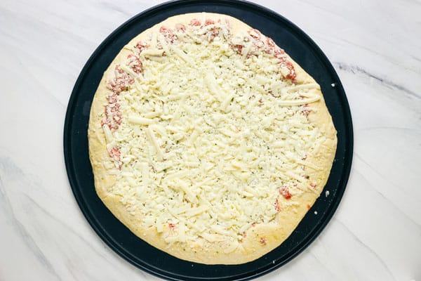 Frozen cheese pizza on a round black pan.