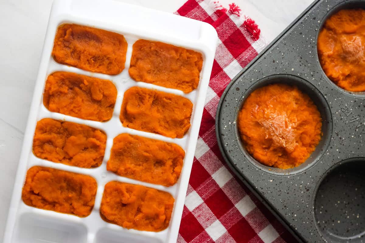 Ice cube tray and muffin tin with frozen pumpkin cubes and cups.