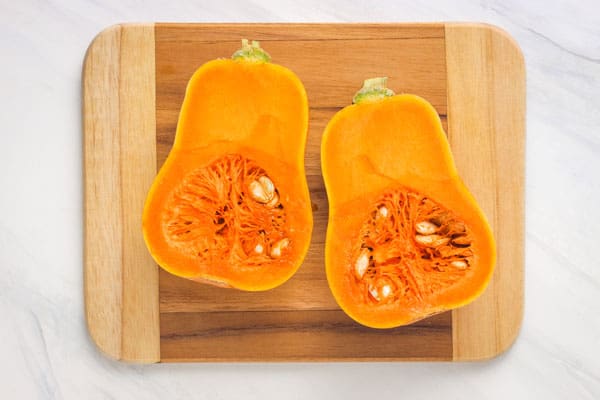 Close up of vibrant orange flesh and seeds inside of a honeynut squash.