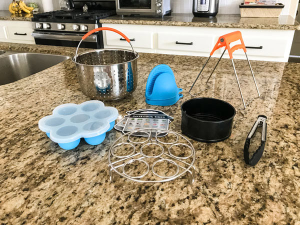 Metal steam basket, small springform pan, plate grabber, egg rack on a kitchen counter.