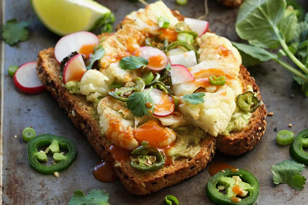 Closeup of cauliflower toast topped with hot sauce and jalapeno slices.