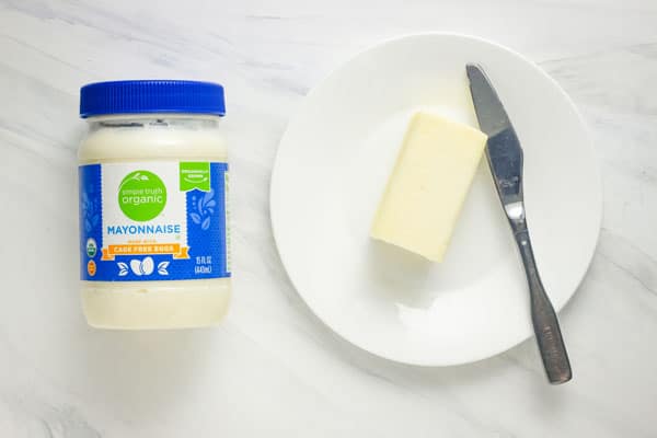 Jar of mayonnaise and plate with stick of butter and a small knife.
