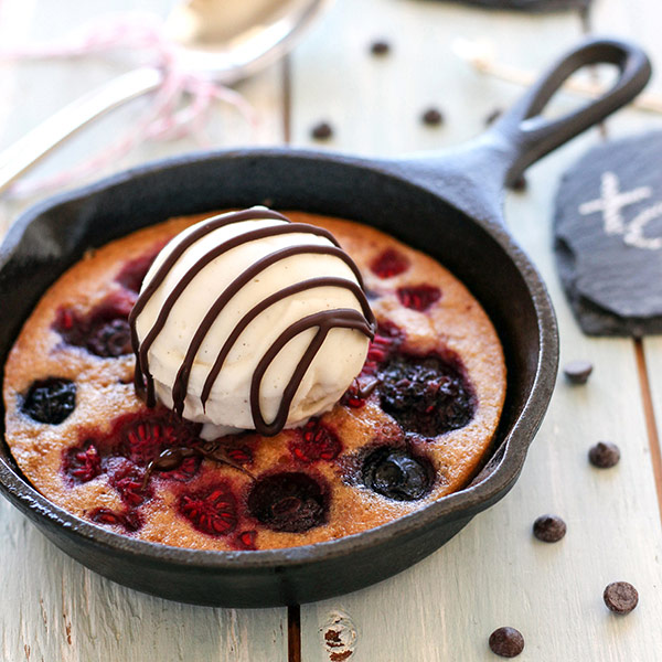 Cake baked in a mini skillet topped with a scoop of ice cream.