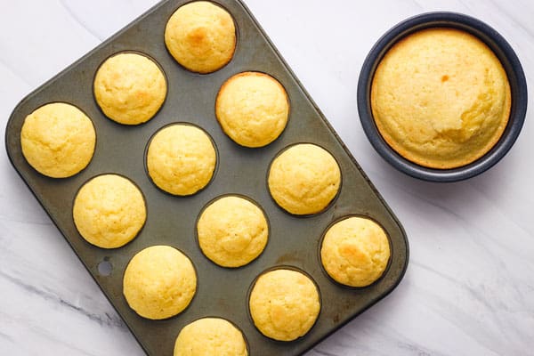 A dozen cornbread mini muffins and small round pan of cornbread.