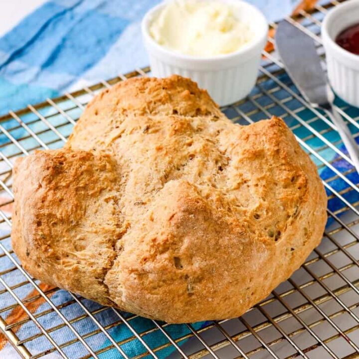 A small loaf of brown soda bread on a cooling rack.