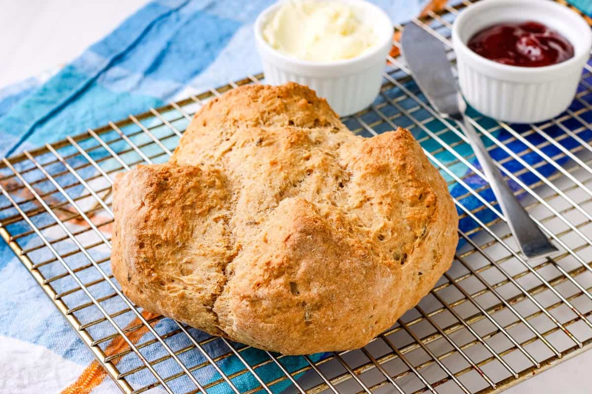 A small loaf of brown soda bread on a cooling rack.