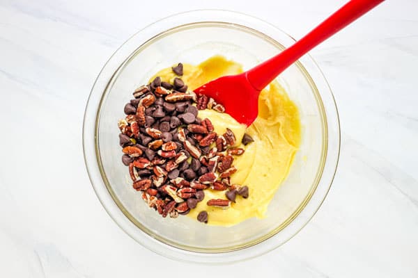 Bowl with mixed cookie batter, chocolate chips, and pecans.