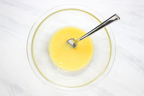 Glass bowl with a fork mixing egg and oil.