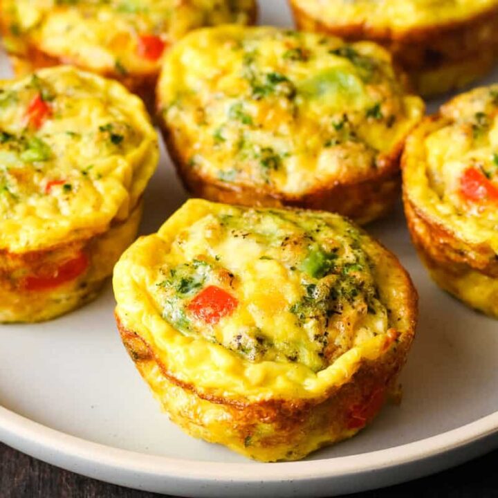 Closeup of six baked frittata muffins on a plate.