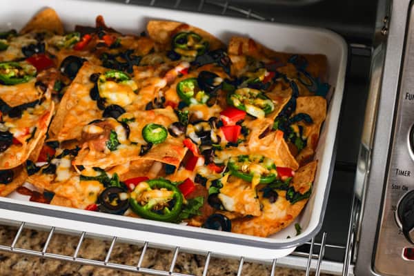Nachos baking on a pan inside of a toaster oven.