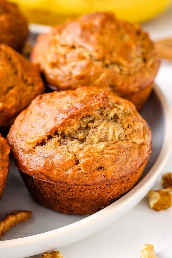 Closeup of a banana oat muffin surrounded by walnuts.