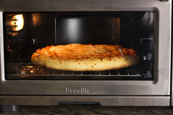 Pizza on cooking rack inside of a toaster oven.