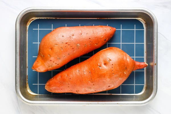 Oiled sweet potatoes on a lined baking pan.
