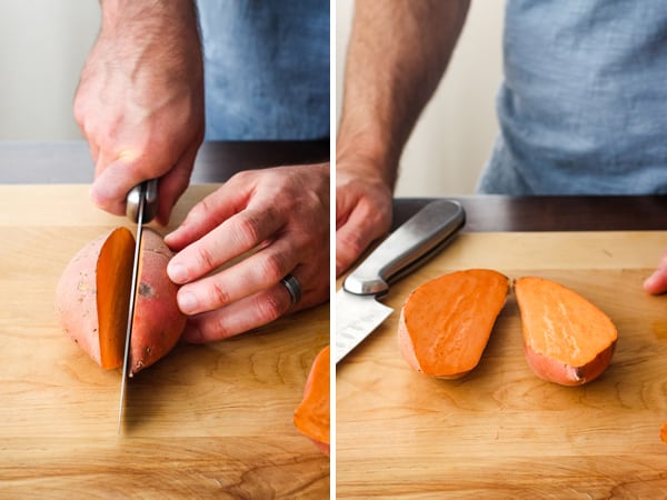 Hands slicing a sweet potato in half on a cutting board.
