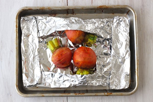 Beets wrapped in foil on a quarter sheet pan