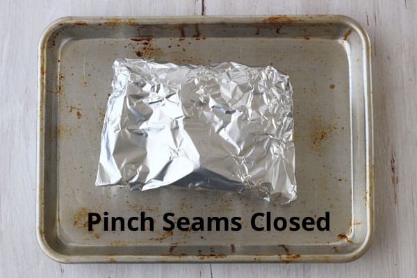 Beets wrapped in foil on a baking pan.