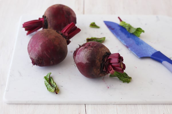 Raw beetroot on a white cutting board.