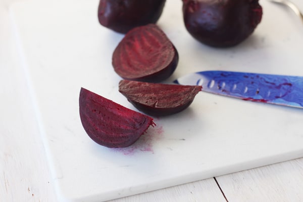Sliced roasted beets on a white cutting board.