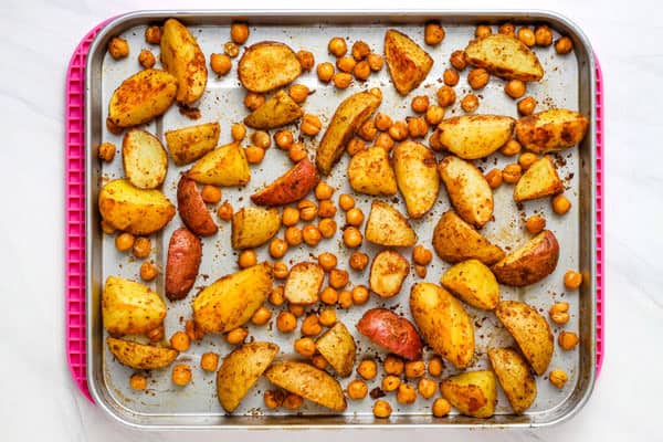 Overhead view of crispy chickpeas and roasted potatoes on a rimmed pan.