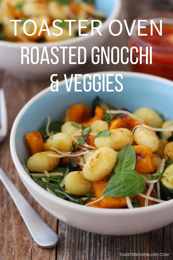 roasted gnocchi and vegetables in a blue bowl on a wooden table.